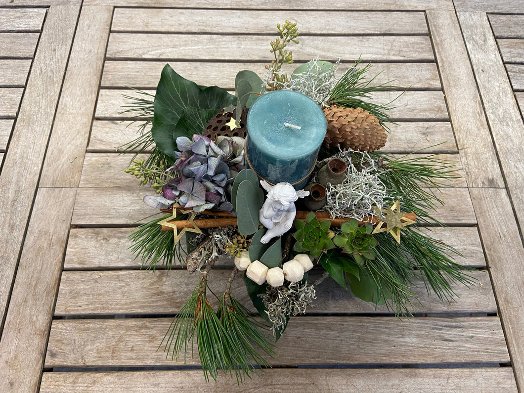 Adventkranz welcher mit viel Liebe gemacht wurde. Rundherum verziert mit Sternchen, Kieferzweigen, Tannenzapfen und vielem mehr. In der Mitte des Kranzes befindet sich eine blauen Kerze sowie auch ein kleiner Ton-Engel.